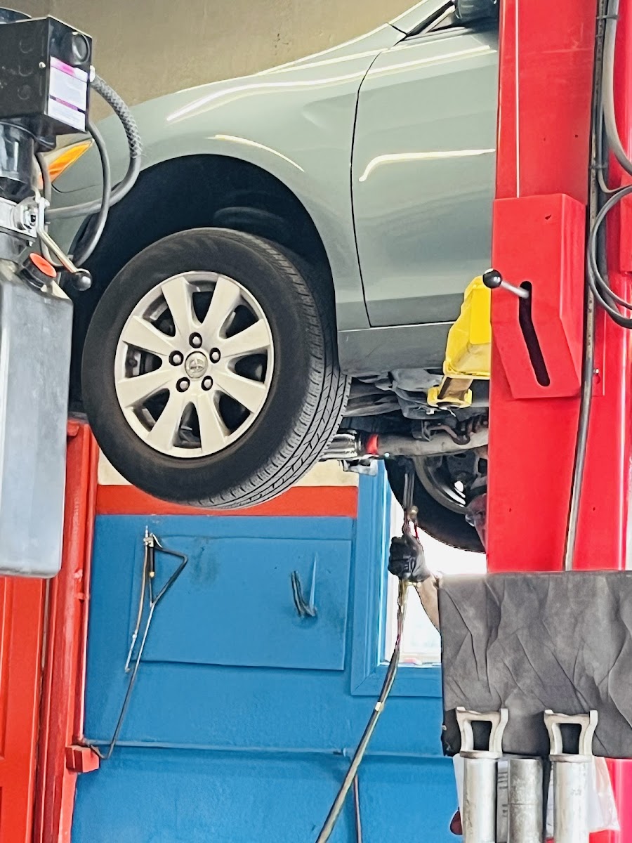 A Toyota raised on the two-post lift inside the shop